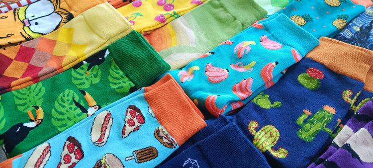 Gros plan sur un assortiment de chaussettes fantaisie aux motifs variés : nourriture, animaux, nature et art, représentant la diversité de la collection Chollala.