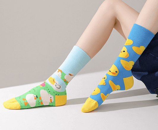 chaussettes fantaisie dépareillées colorées avec motifs canards jaunes et petits poussins sur fond bleu et vert, chaussettes originales et ludiques pour un style fun.