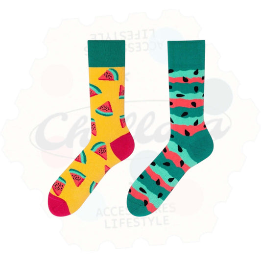 Chaussettes fantaisie dépareillées motif pastèque : une chaussette jaune avec quartiers de pastèque rouge, l’autre à rayures vertes, roses et noires évoquant la peau du fruit.